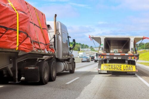 Large trucks carry oversized loads on a crowded highway.