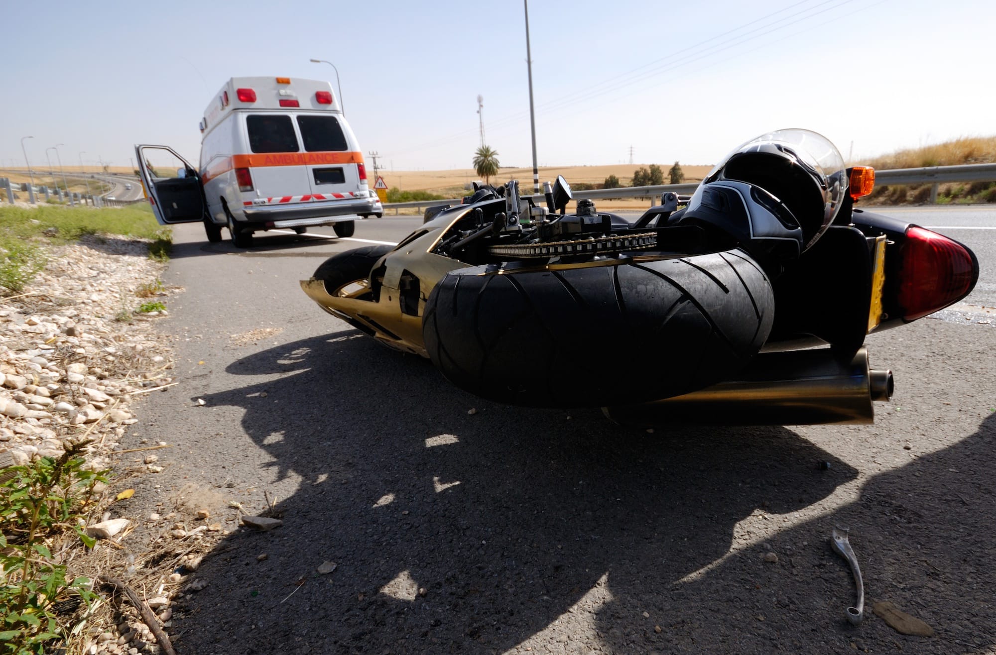 Motorcycle Wreck on the road with an ambulance seen in the background.